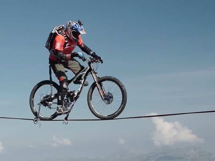 Watch a mountain-biking champion ride across a rope between cliffs in the Alps
