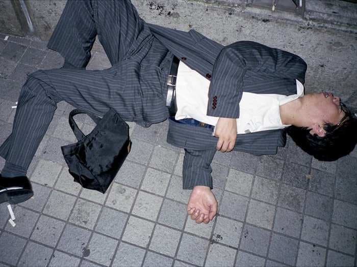 Striking photos of businessmen sleeping on dirty streets illustrate Japan's tireless work culture