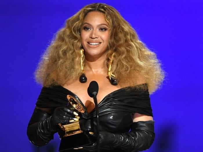 Beyoncé accepted her record-breaking Grammys wearing a form-fitting leather dress, gloves, and massive earrings