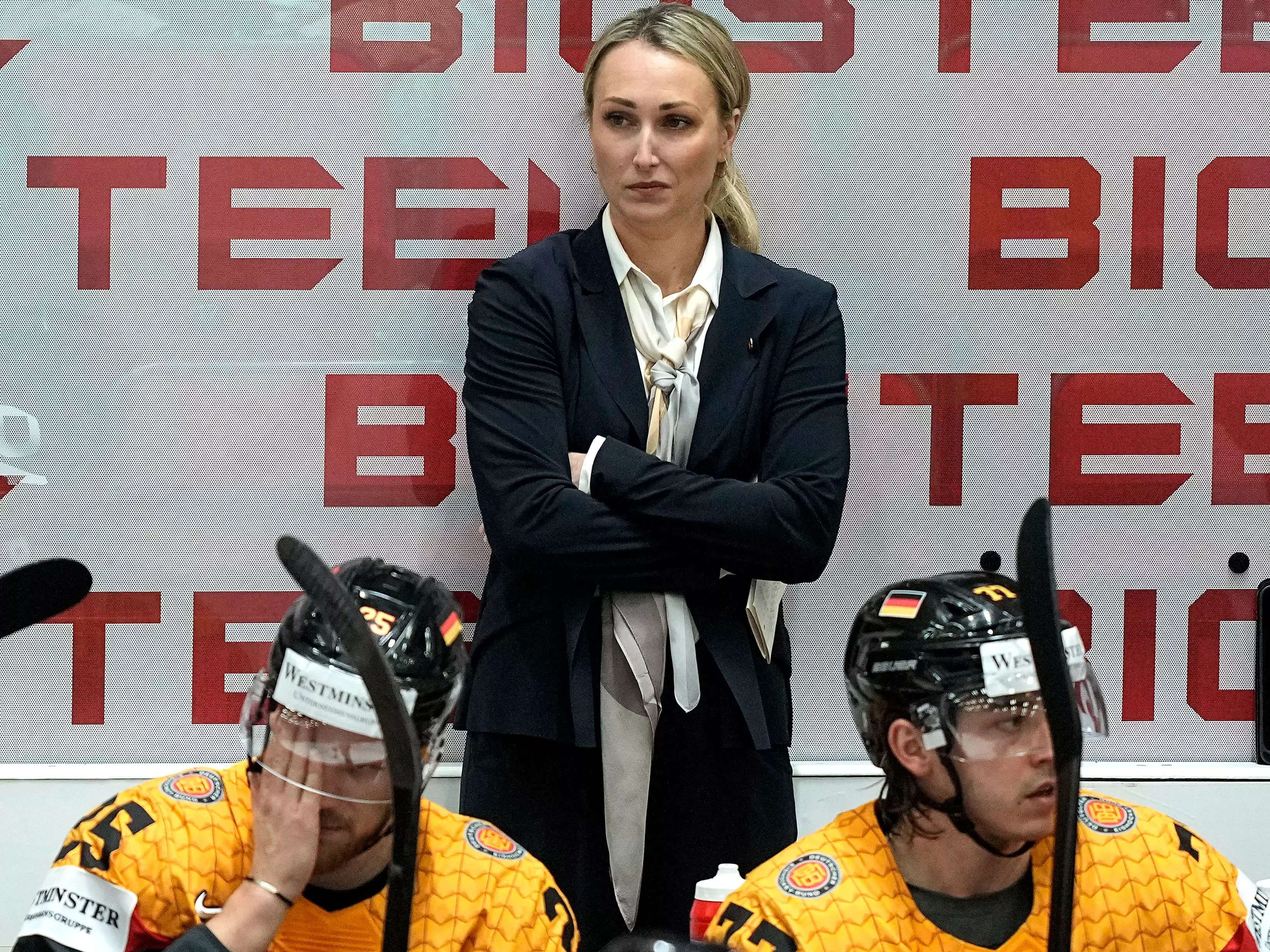 Ein Fernsehreporter fragte die bahnbrechende Trainerin des Team Deutschland, wie es sei, eine „schöne Frau“ in einem Eishockeyteam „voller schöner Männer“ zu sein.