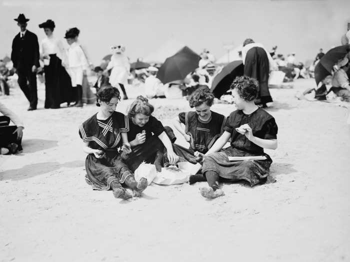 A photo from Coney Island's heyday in 1900 shows a group of modestly dressed young women sharing a meal on the sand.