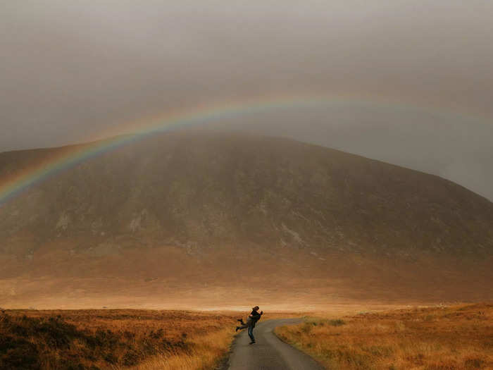 A perfectly placed rainbow elevates this engagement photo taken in Glencoe, Scotland.