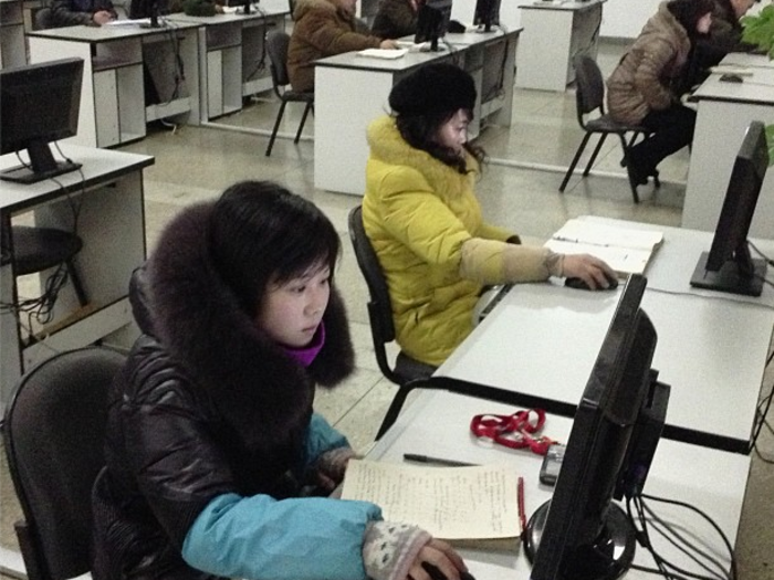 Inside The Grand People's Study House, where students work at computers in winter coats.