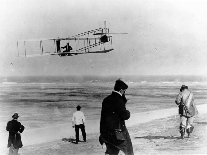 December 17, 1903 - Orville Wright maneuvers the Wright Flyer as it makes its first flight ever over Kitty Hawk, NC. The plane, made of wood, wire, and cloth, traveled 120 feet and flew for 12 seconds.