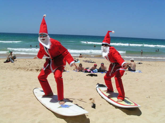 In Australia, Santa Claus pulls up on a surfboard.