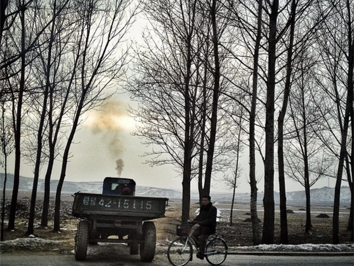 Tractor, wagon, & bicycle in the North Korean countryside.