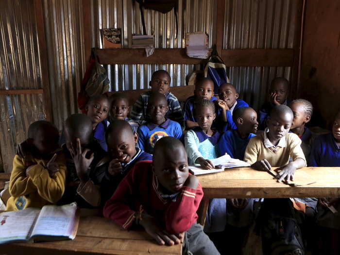 Children between six and seven years old pose in their classroom at Gifted Hands Educational Centre in the Kibera slum of Nairobi, Kenya. In 2003, free education was reintroduced in Kenya — school fees had been the norm since the 1980s.