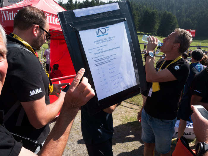 Before each stage of the Tour finishes, an official from the Cycling Anti-Doping Foundation (CADF) posts a list of riders' numbers near the finish line.