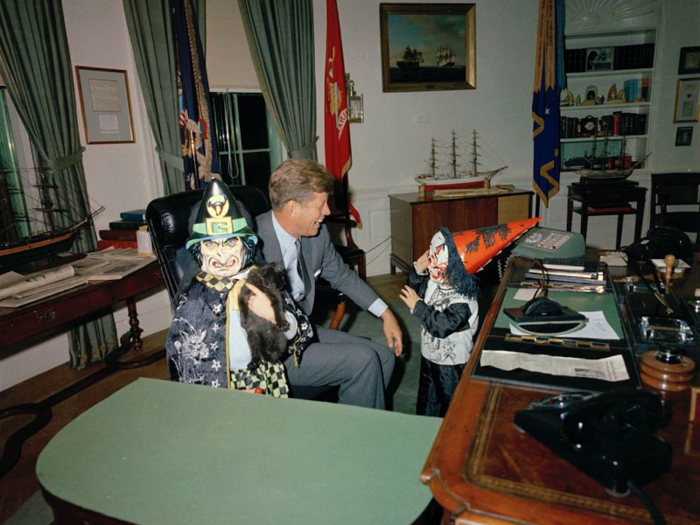 Caroline Kennedy and John F. Kennedy Jr. showing off their Halloween costumes to their father President John F. Kennedy in the Oval Office on October 31, 1963.