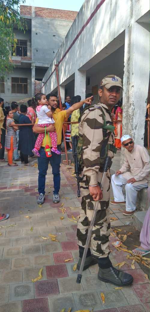 Security personnel outside a polling booth in Greater Noida. Voters queue to cast their votes.