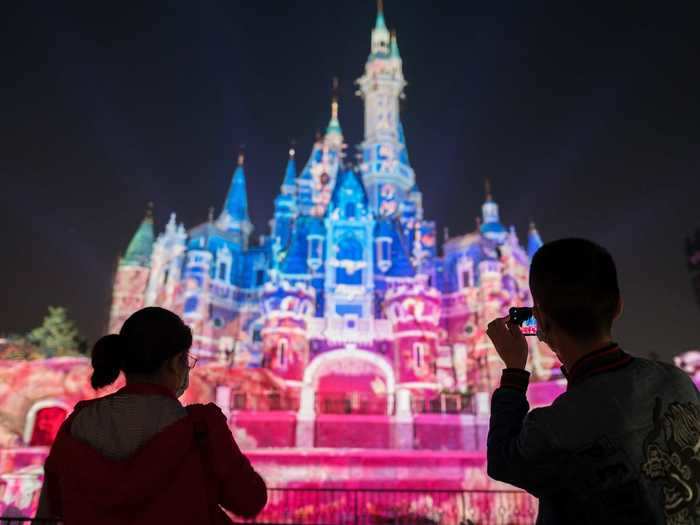Visitors photograph the Disney castle the first night of the park's reopening.