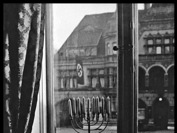 One month before Hitler rose to power, a Jewish family living in Germany defiantly displayed a Hanukkah menorah in their window across from a Nazi flag.