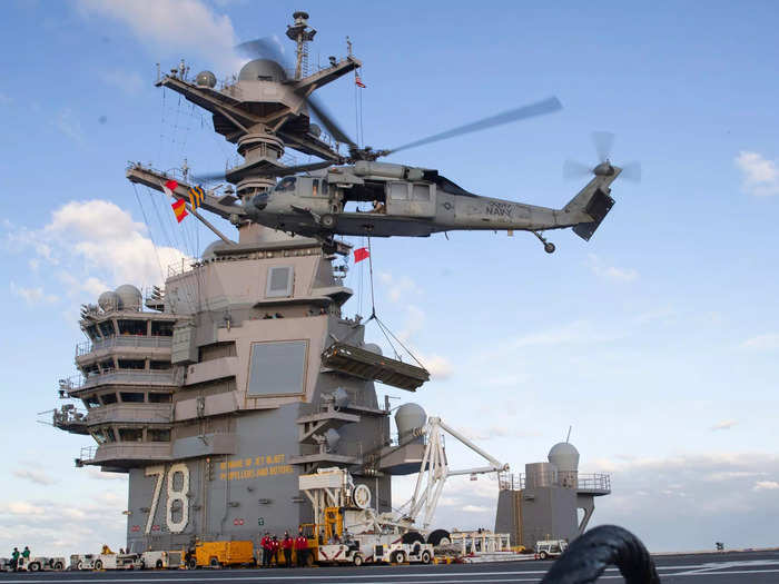 An MH-60S Nighthawk helicopter lands on the flight deck of USS Gerald R. Ford. Behind is the flight command center or the ship's "island" that Trump ranted about.