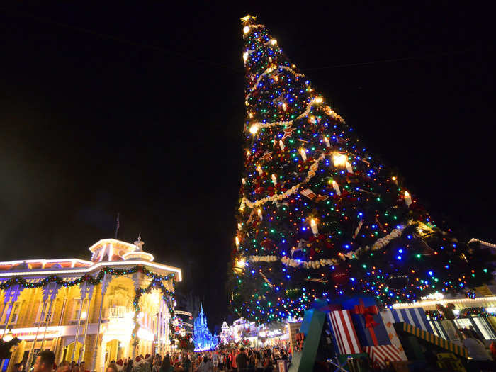 The Christmas tree on Main Street, USA is installed in pieces with a crane.